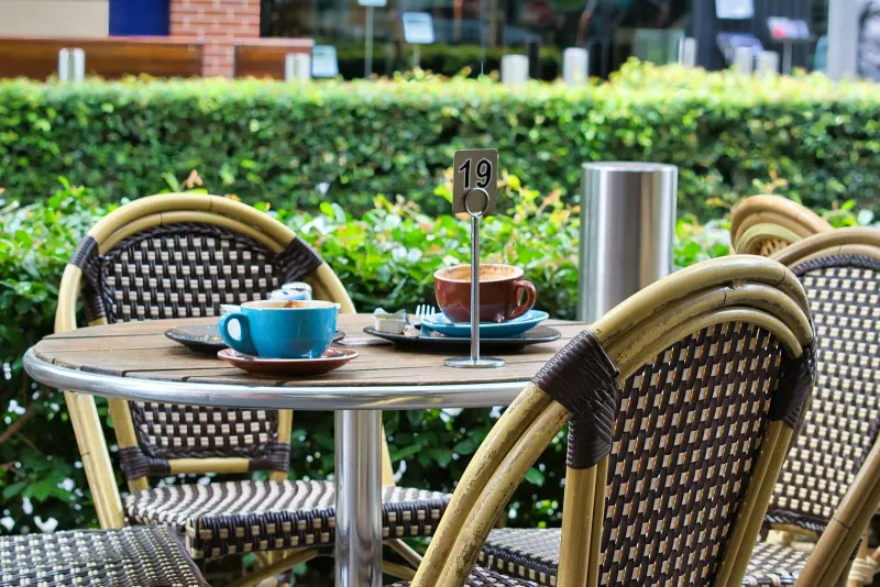 Table de terrasse au matin, deux cafés et des chaises en rotin