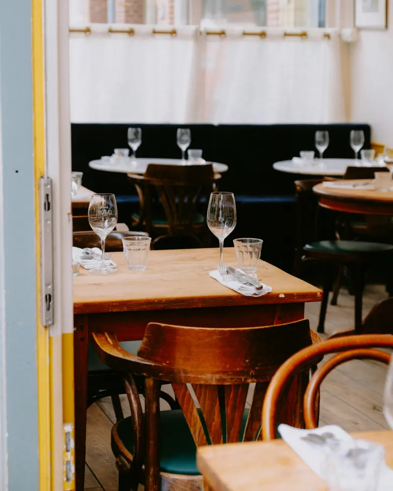 Table en bois et chaises bistrot, verres posés pour le service