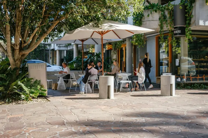 Terrasse de café sous les arbres, parasols ouverts
