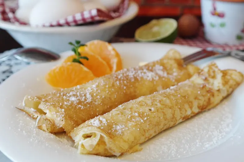Crêpes roulées, quartiers d'orange et sucre glace