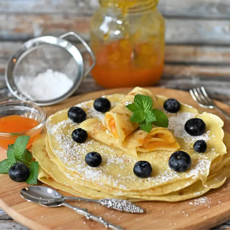 Crêpes aux myrtilles sur une planche de bois, sucre glace
